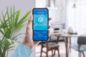 Hand holding phone with a smart app checking air quality in the living room.