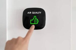 Homeowner touching air quality reader on wall.