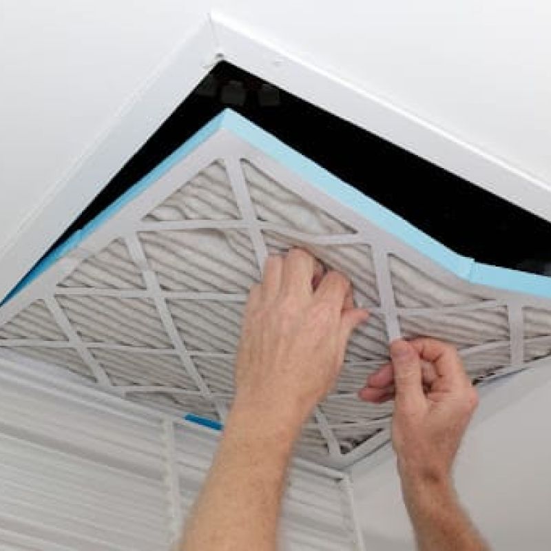 A man replacing an HVAC filter.