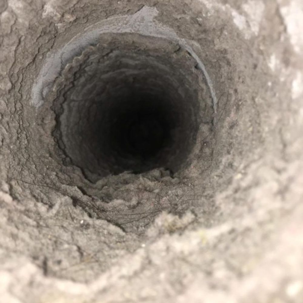 Close-up view of the inside of a dusty, lint-filled dryer vent or duct, showing significant buildup along the interior walls—an issue that can affect both heating and air conditioning efficiency in your HVAC system.