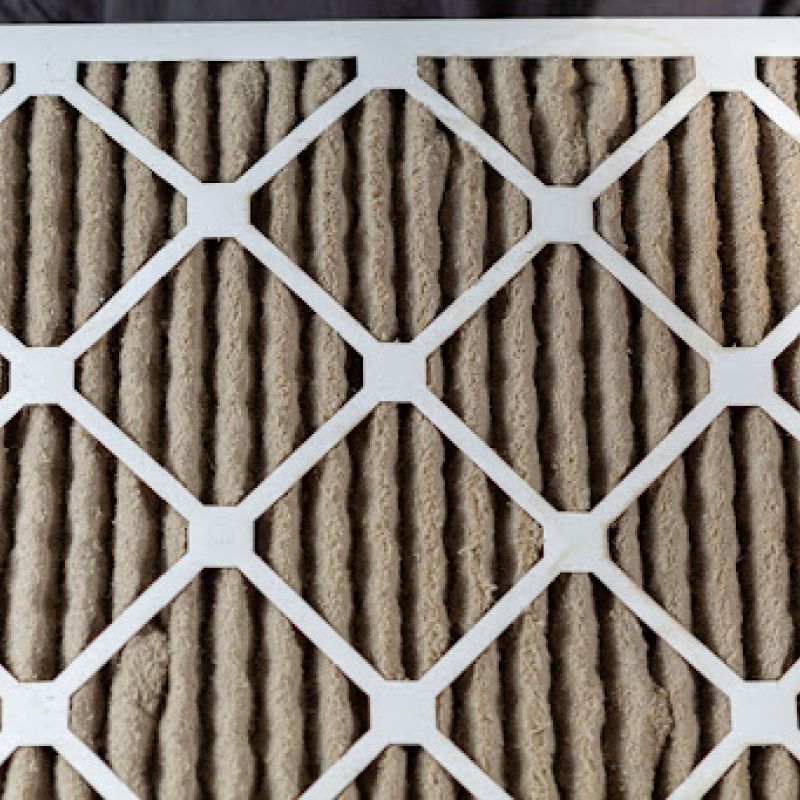 Gloved hands holding a dirty air filter.