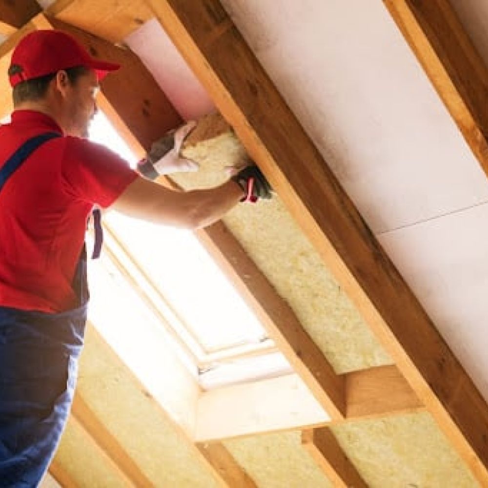 TRIO HVAC expert installing insulation in the roof of a house.