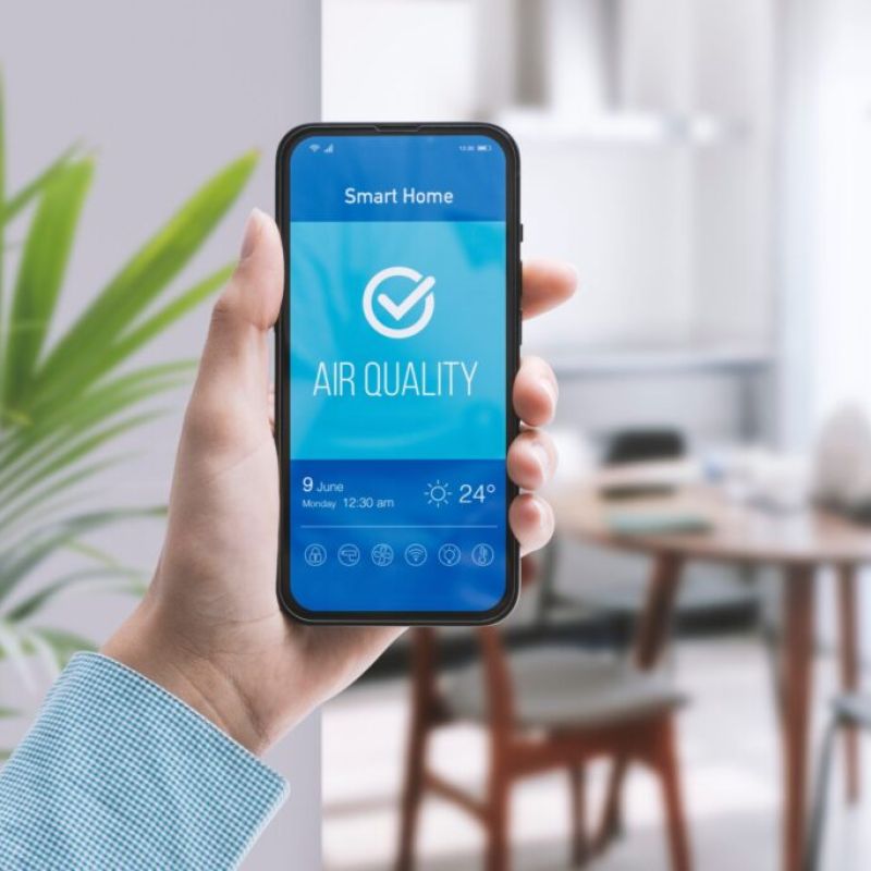 Hand holding phone with a smart app checking air quality in the living room.