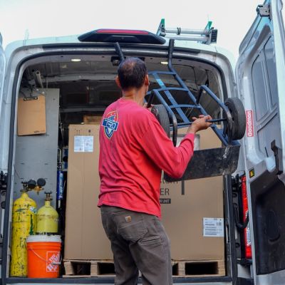 Workers loading equipment into a van for HVAC installation.