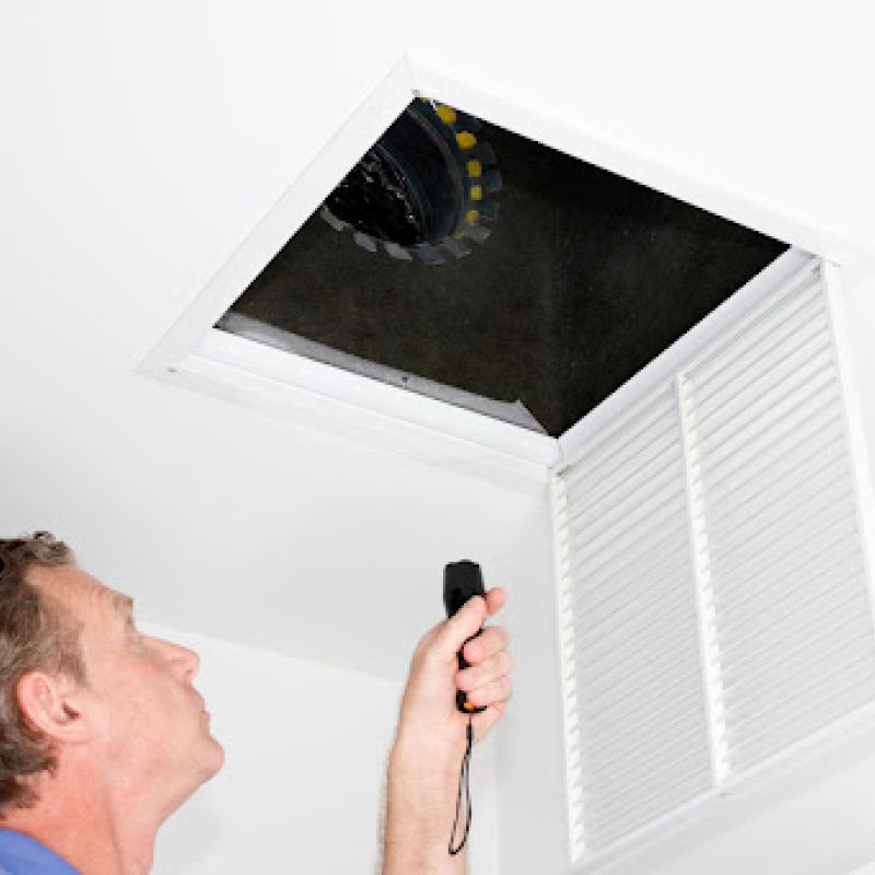 A man looking in a vent and air duct.